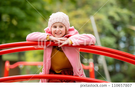 Pretty girl kid standing on playground at autumn day outdoors and daydreaming. Female child happy portrait 110657807