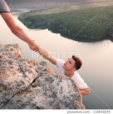 Man help his friend to climb on the rock Man help his friend to climb on the rock 110658059