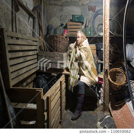 A woman hides in a cellar from shelling 110658062