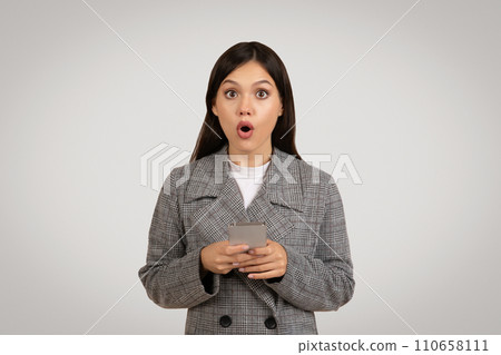 Shocked woman holding phone, surprised by unexpected news Shocked woman holding phone, surprised by unexpected news 110658111