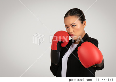 A determined Asian businesswoman in professional attire with boxing gloves is ready to fight A determined Asian businesswoman in professional attire with boxing gloves is ready to fight 110658151