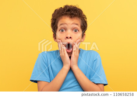 Shocked boy with hands on face, open mouth on yellow background Shocked boy with hands on face, open mouth on yellow background 110658258