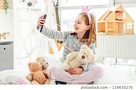 Happy little girl taking photo with toys in cute playroom Happy little girl taking photo with toys in cute playroom 110658270