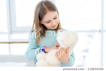 Cute little girl holding teddy bear in mask 110658398