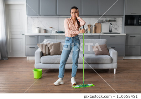 Weary woman with mop needing break from cleaning 110658451