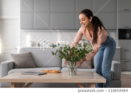 Woman adorning table with fresh plant in vase Woman adorning table with fresh plant in vase 110658464