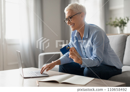 senior woman shopping using laptop and holding credit card indoor senior woman shopping using laptop and holding credit card indoor 110658492