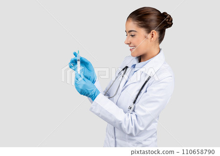 Cheerful millennial caucasian lady doctor in white coat show syringe with vaccine Cheerful millennial caucasian lady doctor in white coat show syringe with vaccine 110658790