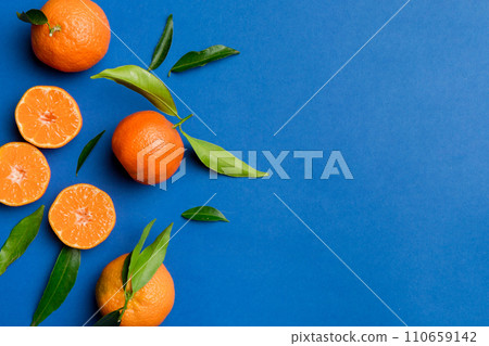 Many fresh ripe mandarin with green leaves on colored background, top view, space for text 110659142
