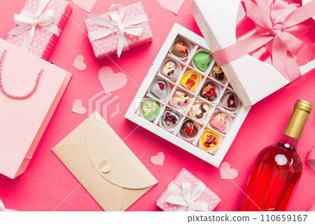 top view photo of st valentine day decor shopping, bag, wine, bottle, envelope, gift, box, candy and red heart on colored background with empty space. Frame background 110659167