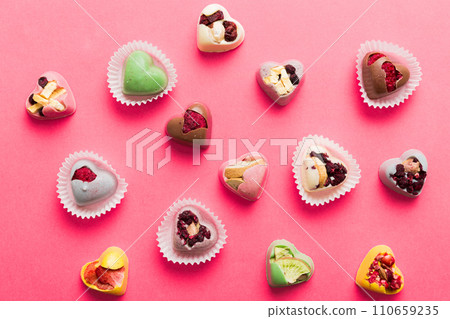 chocolate sweets in the form of a heart with fruits and nuts on a colored background. top view with space for text, holiday concept 110659235