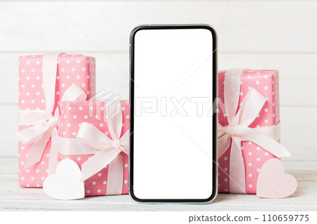 mobile phone with blank screen on colored background with hearts, calendar and gift box, valentine day concept perspertive view flat lay 110659775