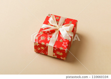 Wrapped christmas or other holiday handmade present in paper with colored ribbon. Present box, decoration of gift on table, top view with copy space Wrapped christmas or other holiday handmade present in paper with colored ribbon. Present box, decoration of gift on table, top view with copy space 110660104
