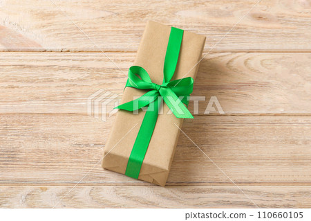 Wrapped christmas or other holiday handmade present in craft paper with colored ribbon. Present box, decoration of gift on table, top view with copy space Wrapped christmas or other holiday handmade present in craft paper with colored ribbon. Present box, decoration of gift on table, top view with copy space 110660105