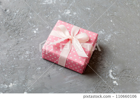 wrapped Christmas or other holiday handmade gift box in color paper with ribbon on colored background. Present box, decoration of gift on colored table, top view with copy space wrapped Christmas or other holiday handmade gift box in color paper with ribbon on colored background. Present box, decoration of gift on colored table, top view with copy space 110660106