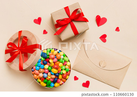 Red envelope with candy and gift box and Valentines hearts on colored background. Flat lay, top view. Romantic love letter for Holiday concept Red envelope with candy and gift box and Valentines hearts on colored background. Flat lay, top view. Romantic love letter for Holiday concept 110660130