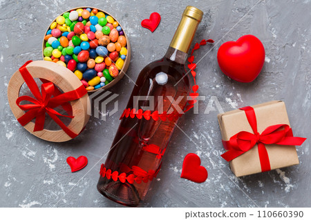 Bottle of red wine on colored background for Valentine Day with gift and chocolate. Heart shaped with gift box of chocolates top view with copy space Bottle of red wine on colored background for Valentine Day with gift and chocolate. Heart shaped with gift box of chocolates top view with copy space 110660390