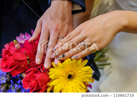 男人和女人的手上有一束紅玫瑰和戒指、結婚戒指、新娘和新郎的手 110661719