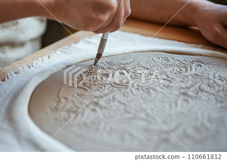 Potter is cutting out the shape of the future plate from the clay layer. Unplugging, hobby 110661812