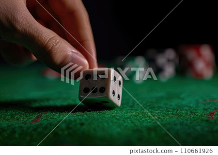 Close up of male hand rolling the dice on green poker table with black background 110661926