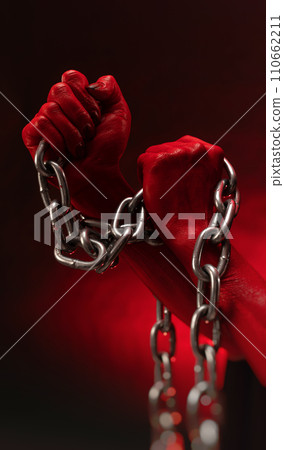bloodied hands clenched into fists in the shackles of a metal chain symbolize slavery, protest and the struggle for freedom bloodied hands clenched into fists in the shackles of a metal chain symbolize slavery, protest and the struggle for freedom 110662211