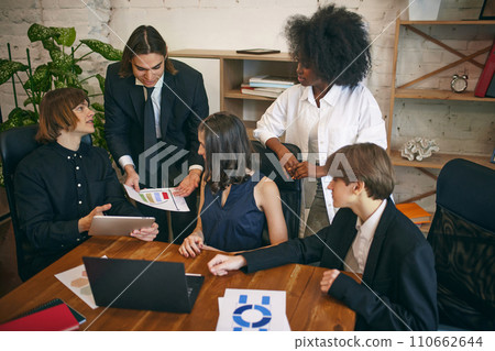 Group of young multiracial business people working and communicating together in creative office with head of department. 110662644