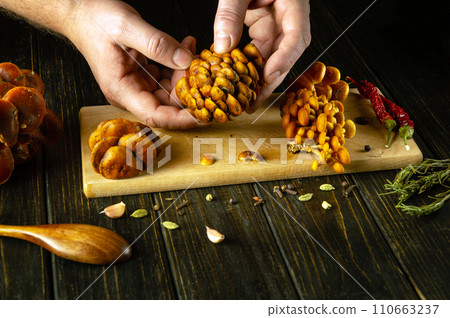 Sorting Flammulina velutipes mushrooms on a kitchen table by the hands of a cook. The concept of preparing dietary Velvet shank for lunch with aromatic spices in a restaurant or in a hotel kitchen 110663237