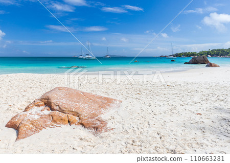 Coastal rock lays on white sand on a sunny summer day. Landscape of the Anse Lazio beach Coastal rock lays on white sand on a sunny summer day. Landscape of the Anse Lazio beach 110663281