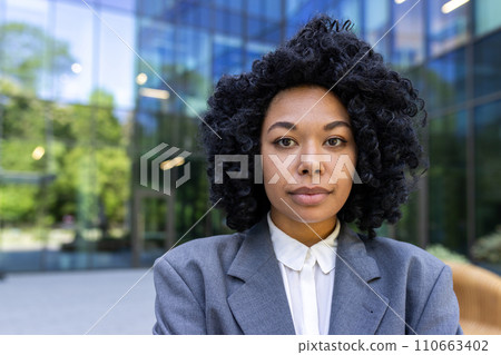 Portrait of a serious African American female student standing outside campus wearing a suit and looking confidently at the camera. Close-up photo. Portrait of a serious African American female student standing outside campus wearing a suit and looking confidently at the camera. Close-up photo. 110663402