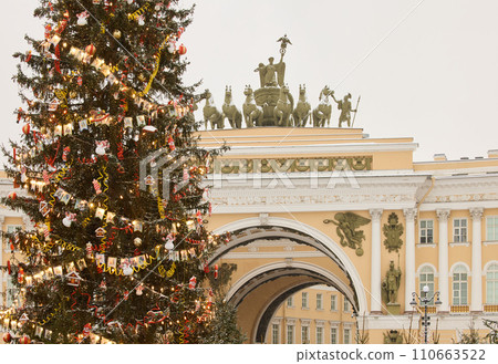 The main Christmas tree shimmers with lights of decorations, the central Palace square of the city decorated for the celebration during the snowfall, Arch of the General Staff, flag of Armed Forces The main Christmas tree shimmers with lights of decorations, the central Palace square of the city decorated for the celebration during the snowfall, Arch of the General Staff, flag of Armed Forces 110663522