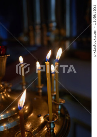 Burning church candles in a gilded candlestick in a temple in the dark 110663652