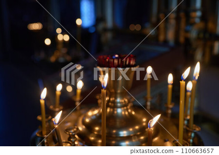 Burning church candles in a gilded candlestick in a temple in the dark 110663657