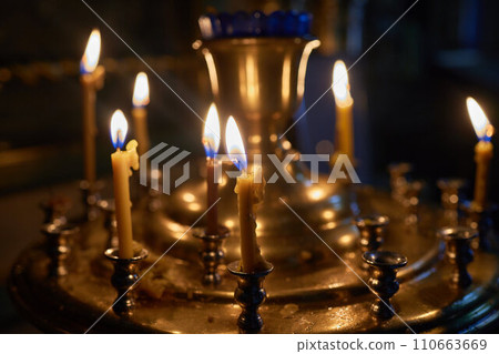 Burning church candles in a gilded candlestick in a temple in the dark 110663669
