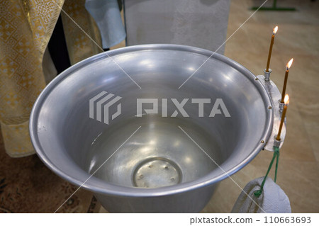 Newborn baby baptism in Holy water. baby holding mother's hands. Infant bathe in water. Baptism in the font. Sacrament of baptism 110663693