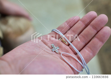 Newborn baby baptism in Holy water. baby holding mother's hands. Infant bathe in water. Baptism in the font. Sacrament of baptism 110663698