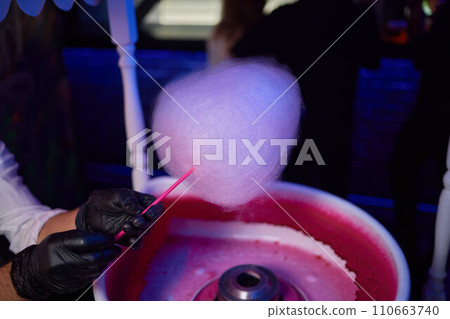 Hand rolling cotton candy in candy floss machine. Making candyfloss Hand rolling cotton candy in candy floss machine. Making candyfloss 110663740