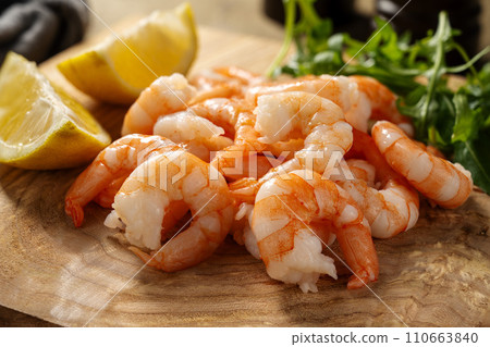 Cooked shrimps with lemon on wooden board. Cooked shrimps with lemon on wooden board. 110663840
