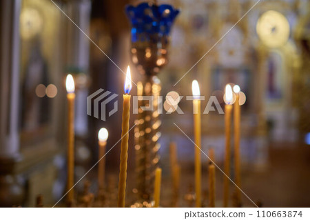 Burning church candles in a gilded candlestick in a temple in the dark 110663874