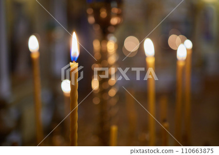 Burning church candles in a gilded candlestick in a temple in the dark Burning church candles in a gilded candlestick in a temple in the dark 110663875