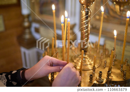 Burning church candles in a gilded candlestick in a temple in the dark 110663879