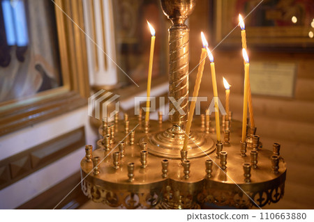 Burning church candles in a gilded candlestick in a temple in the dark 110663880