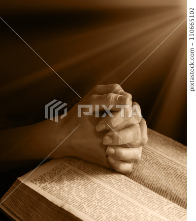 Hands clasped in prayer near an open book Hands clasped in prayer near an open book 110665102