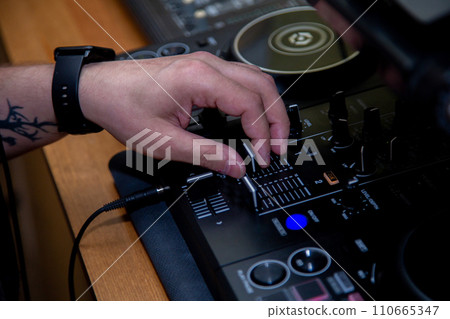 A DJ in a nightclub at the control panel adjusts the music. Music is playing, creating an atmosphere. High quality photo A DJ in a nightclub at the control panel adjusts the music. Music is playing, creating an atmosphere. High quality photo 110665347