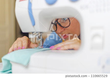 Concentrated Woman Sewing on a White Machine 110665529