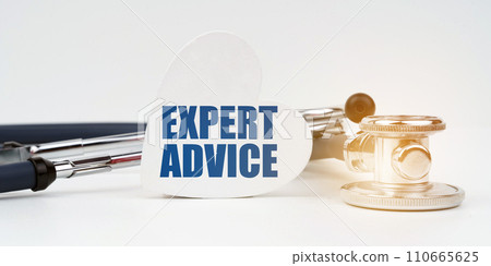 On the white surface there is a stethoscope and a heart plate with the inscription - EXPERT ADVICE 110665625