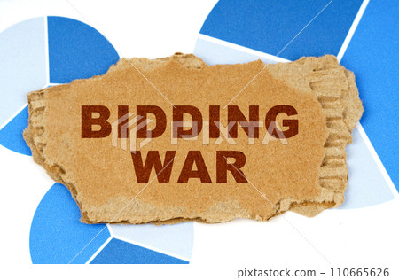 On the blue financial charts is a piece of cardboard that says - Bidding War 110665626