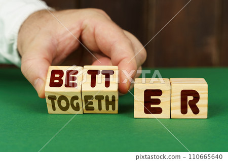 On a green surface, a man puts cubes with the inscription - BETTER, TOGETHER 110665640