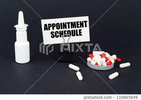 On a black surface are pills, a nasal spray and a paper sign with the inscription - APPOINTMENT SCHEDULE 110665649