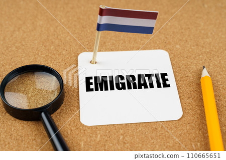On the table is the flag of the Netherlands, a pencil and a sheet of paper with the inscription - Emigration On the table is the flag of the Netherlands, a pencil and a sheet of paper with the inscription - Emigration 110665651