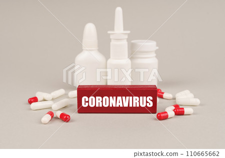 On a gray surface are pills, white jars and a red wooden block with the inscription - Coronavirus 110665662